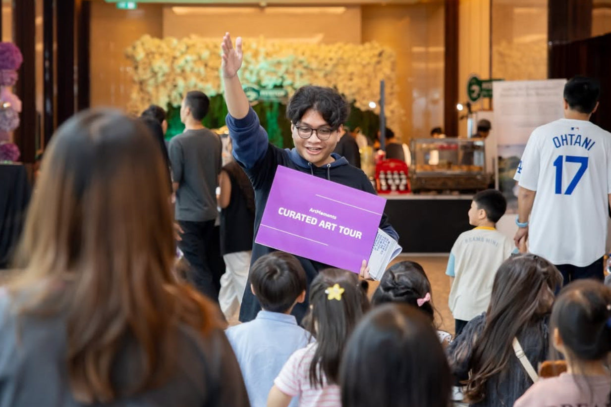 Person holding a purple sign with text, standing in front of a group of people in an indoor setting.